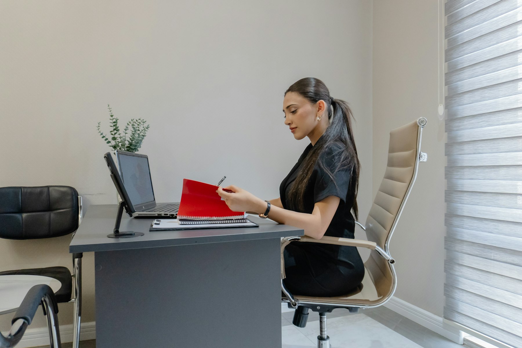 An HR professional reviewing a red folder at her desk in a bright office